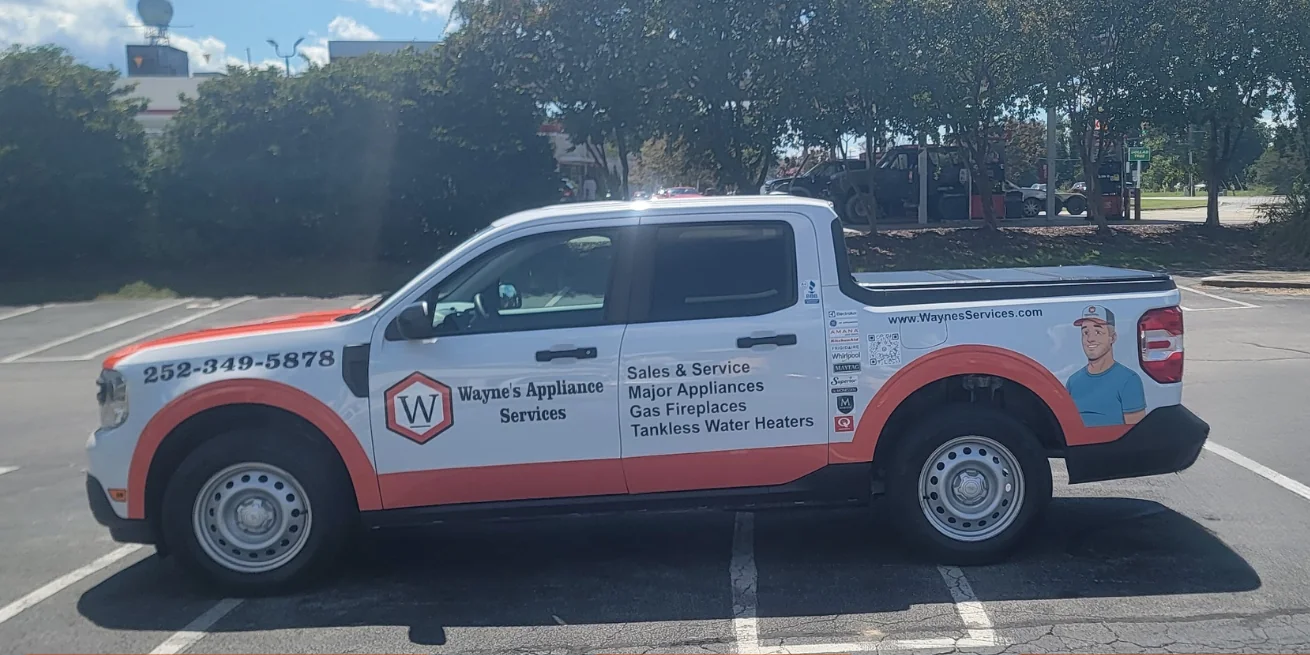 Wayne's Appliance Services Ford Maverick with a white and orange partial wrap — hexagonal W logo and phone number on the front door, a four-line service list on the rear door, manufacturer authorization badges and a QR code behind it, and an illustrated technician on the bed panel.
